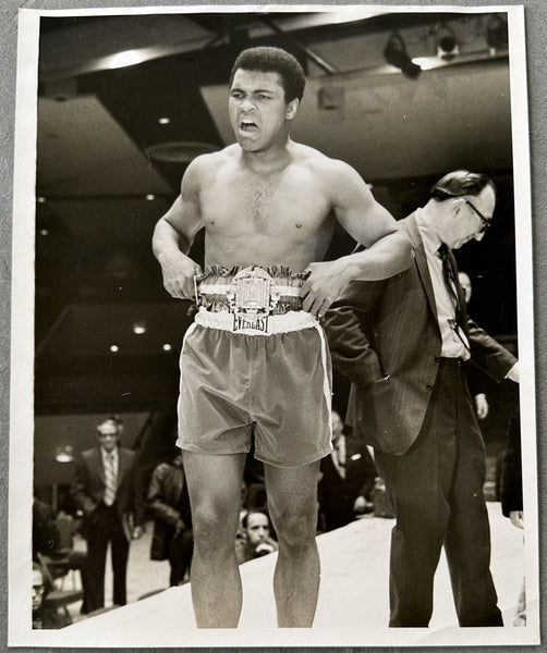 ALI, MUHAMMAD DISPLAYING HIS BELT TYPE 1 PHOTOGRAPH (1971-AT FRAZIER PRE FIGHT PHYSICAL)